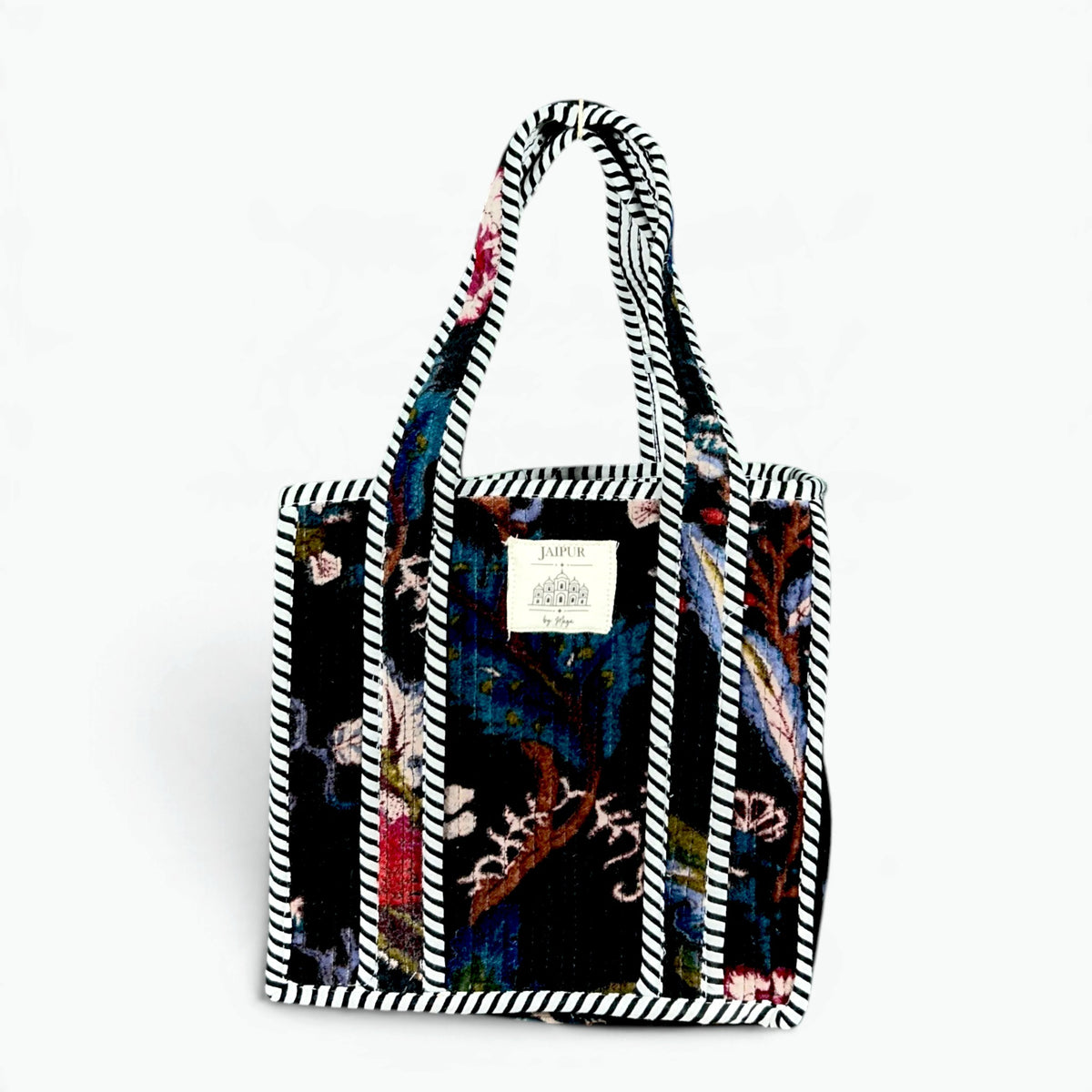 Black quilted velvet tote bag with botanical print in teal, red and lavender and black and white striped piping and handles