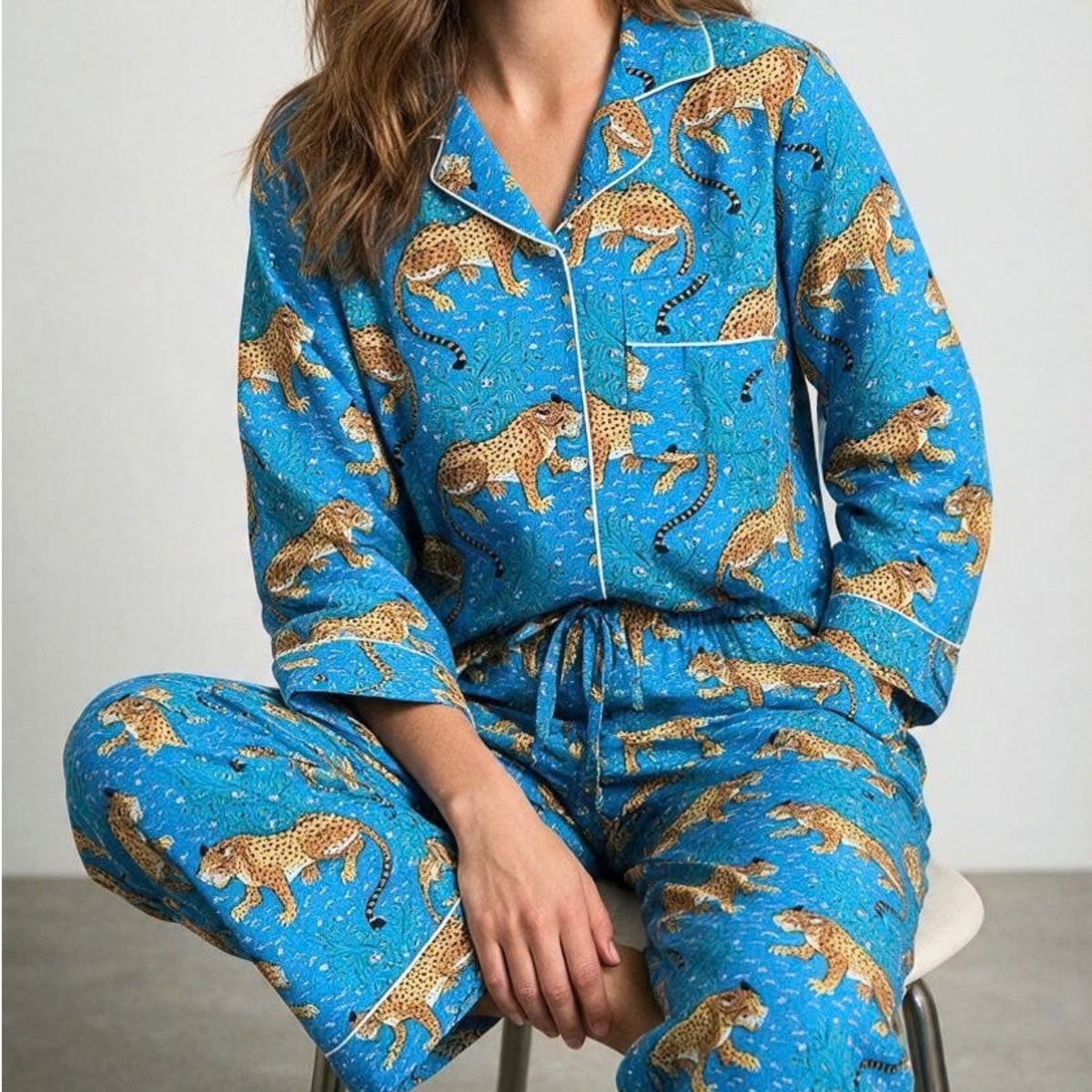 Bright blue cotton pyjama set featuring a leopard and botanical print with white piping, shown with a matching fabric pouch.
