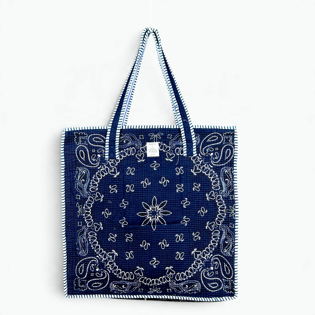 Navy blue quilted cotton tote bag with white bandana paisley print and navy and white striped piping and handles