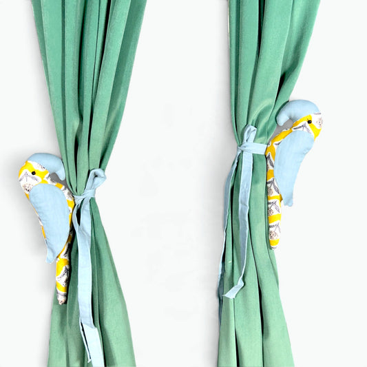 Pair of powder blue and yellow floral parrot curtain tiebacks on green velvet curtains