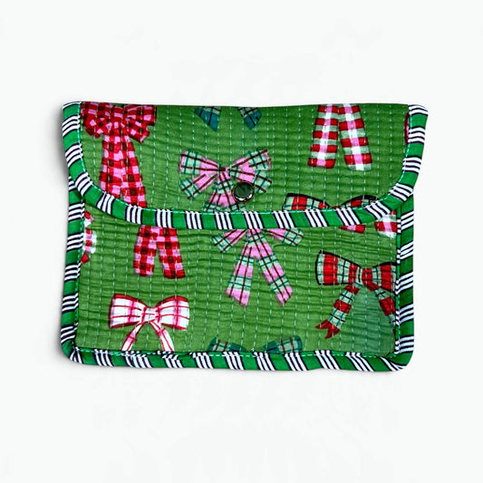 A green quilted fabric pouch featuring a festive holiday print with red and white gingham bows, plaid accents, and striped trim, shown against a plain white background.