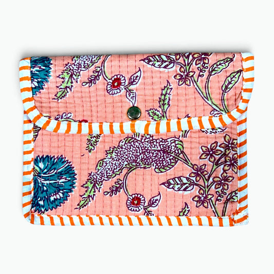A quilted fabric pouch or notebook cover featuring a pink background with a purple bird and floral pattern, finished with orange and white striped borders and a snap button closure.