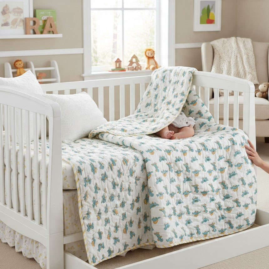 Reversible cotton toddler quilt shown on a child's bed and cot, featuring a light green chevron pattern on one side and a blue dinosaur print on the other.